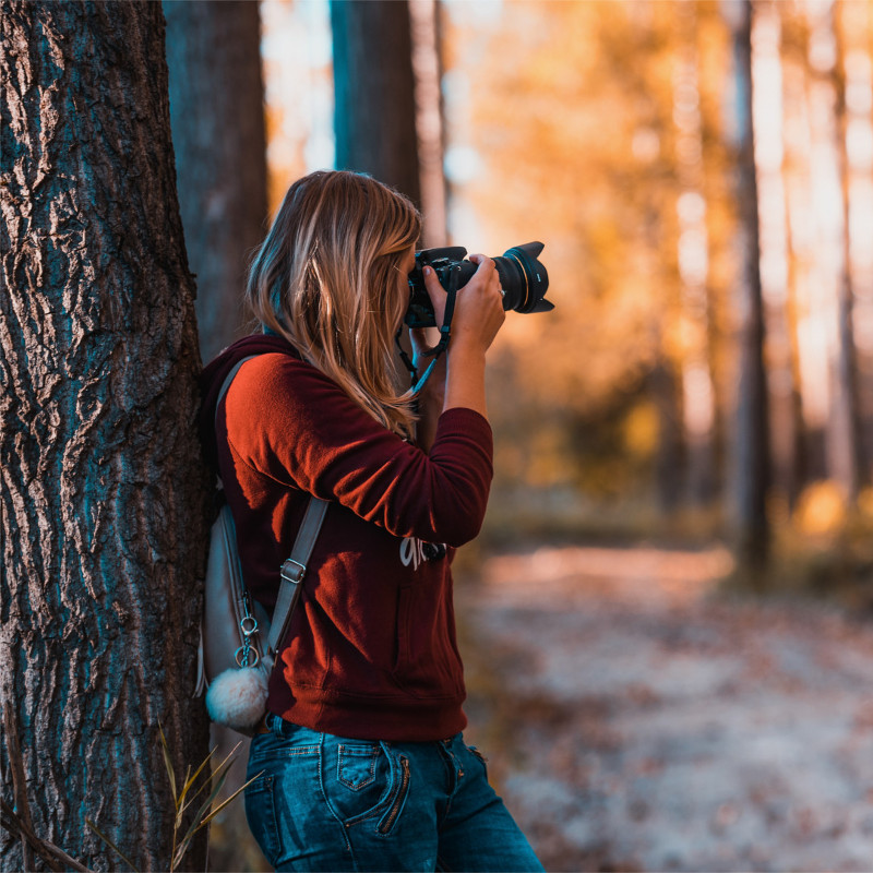 Woman with camera taking photos in the woods