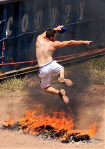 man jumping over fire pit