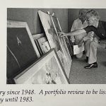 Two men reviewing large framed artworks leaning against a wall during a portfolio review.