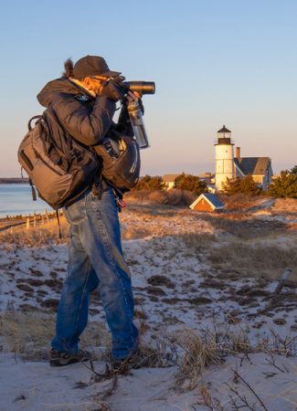Photographer capturing lighthouse during sunset.