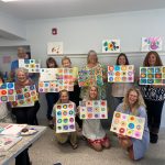 Group proudly displaying colorful circle artwork during studio session.