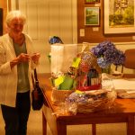 Elderly woman viewing gift items in warmly lit gallery.