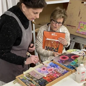 Two women working with pastel flower art