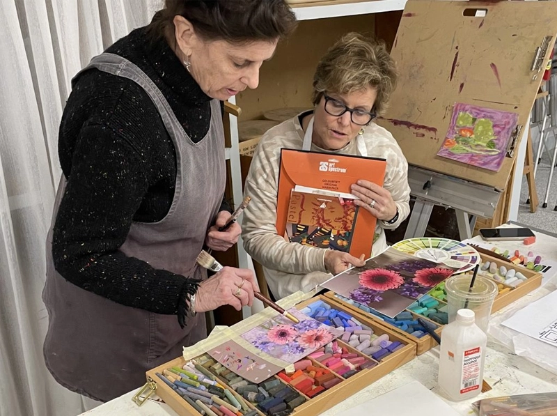 Two women working with pastel flower art
