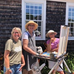 Outdoor painters smiling near easel in bright sunny yard.
