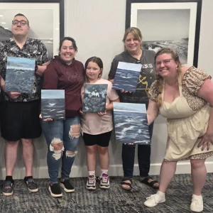 Group holding paintings, smiling indoors
